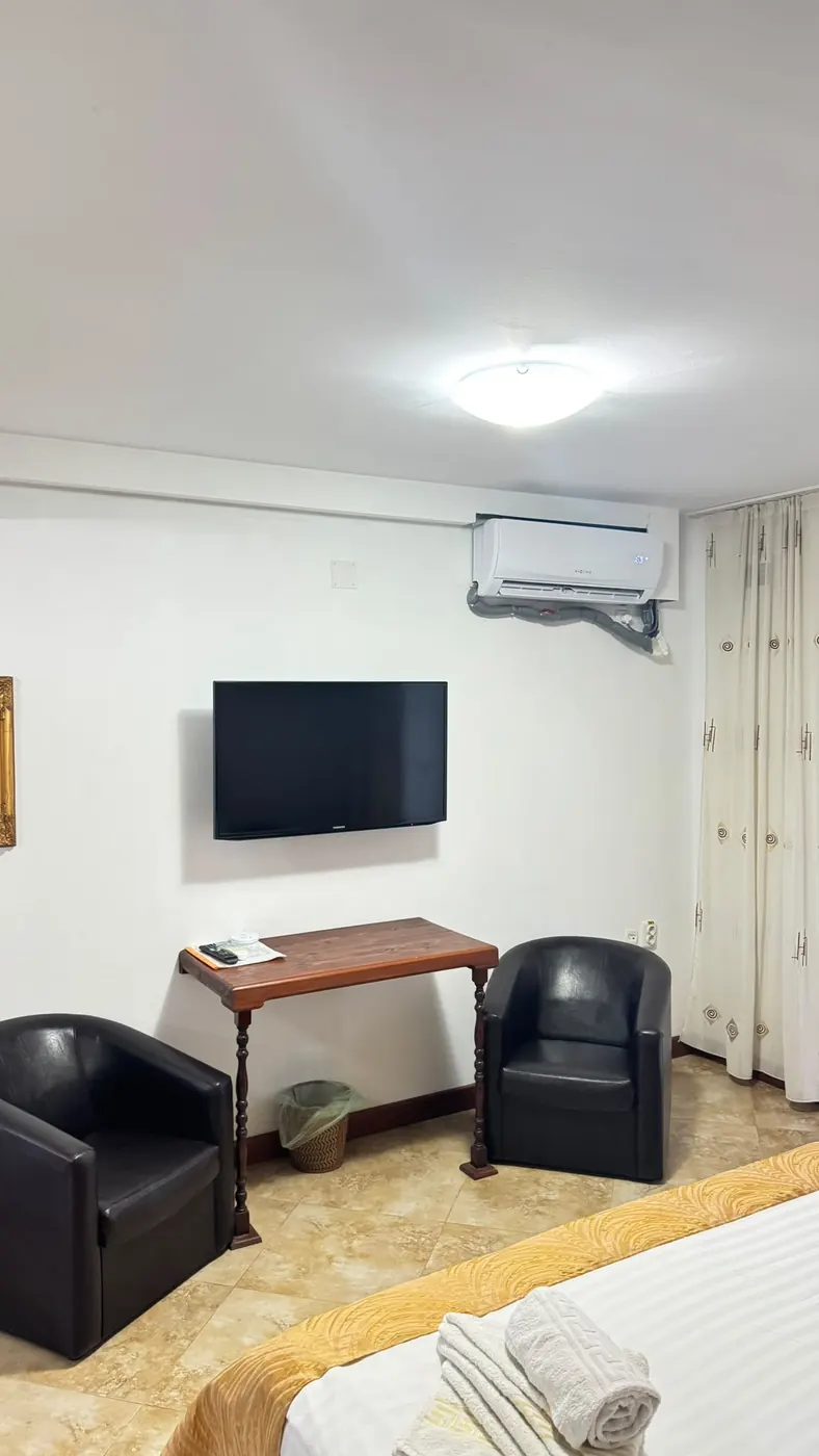 Cameră spațioasă cu televizor, masă și două fotolii