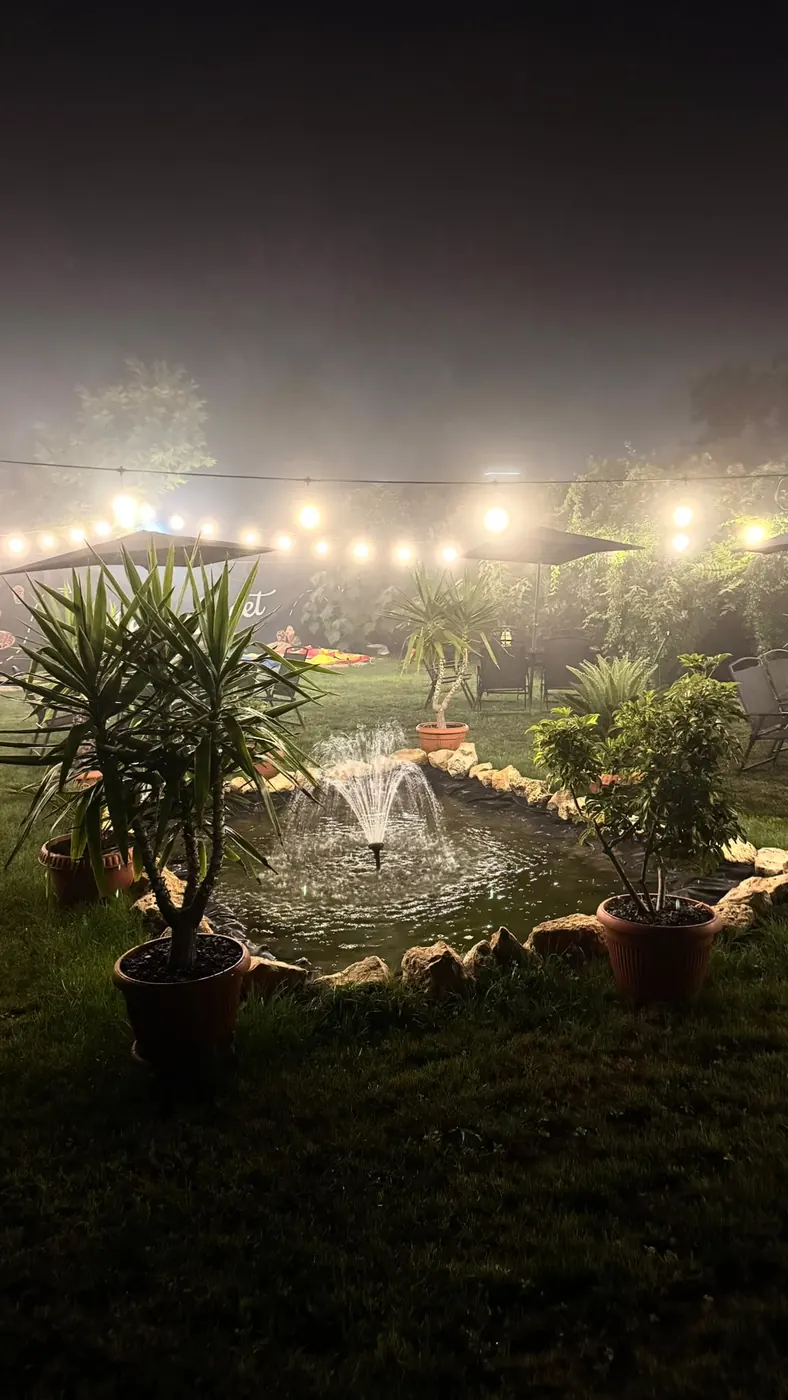 Fântâna arteziană din curte, iluminată seara